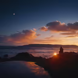 a person sitting on rocks watching the sun set