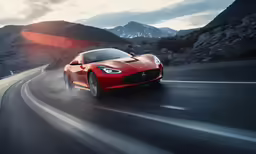 a red sports car going down a mountain road