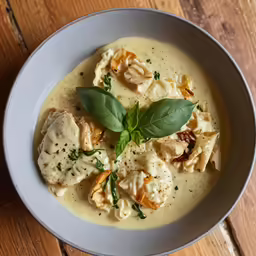 a bowl full of pasta and cheese with a fresh green leaf on top