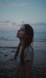 a woman is standing on the beach looking up