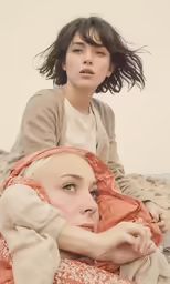 two women pose for the camera under blankets