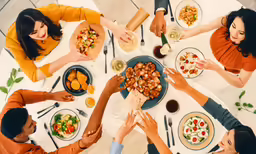 a group of people are around a table eating food
