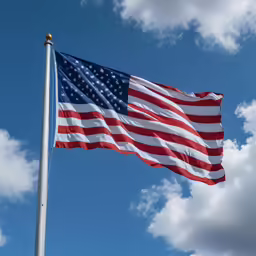 an american flag flying in the sky with clouds