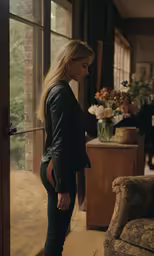 a blonde woman stands in front of a glass door