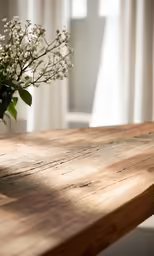 a vase with flowers sits on a wooden table