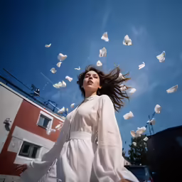 a beautiful woman in a white dress throwing paper around
