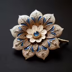 gold plated brooch with a blue and white flower on black background