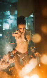 the man is shirtless holding a pipe and burning candles