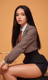 a young woman posing in a skirt and brown jacket