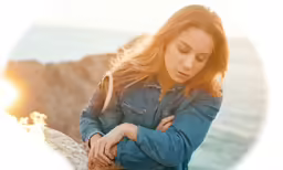 a woman is looking down while standing by the water