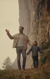 a man holding the hand of a child while walking next to a rock formation