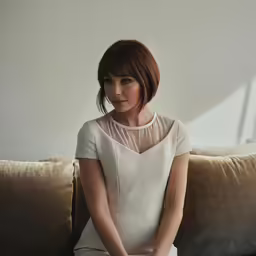 a woman sitting on top of a couch with her legs crossed
