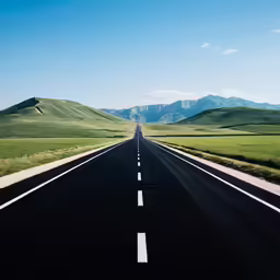 an empty road stretches into the distance as mountains rise in the distance