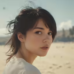 a girl looks to her right while standing in front of some sand