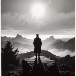 a man is standing on a cliff with foggy mountains