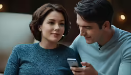 a man and woman sitting together on a couch using cell phones