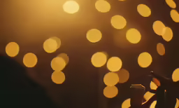 a person holds up a lit cup with a candle behind it