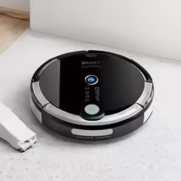 a robotic vacuum sits next to its charging cable