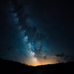 a road runs through a field under the sky at night