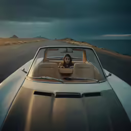 a woman is sitting in a car near the ocean