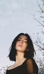a woman looking into the distance near a tree