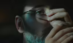 a man with glasses covering his eyes looking up