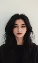 a woman standing against a white wall