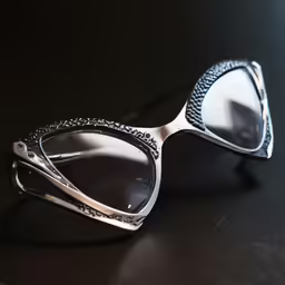a pair of silver colored glasses sit on a black surface