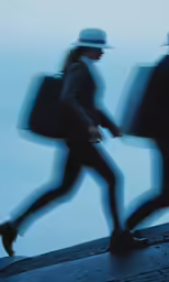 a blurry photo shows two people wearing helmets and carrying suitcases