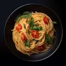 a black plate with spaghetti and tomatoes