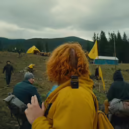 a person with curly hair and a backpack is standing in a field