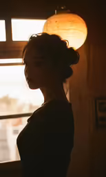 a girl in dark clothes and a light bulb on a windowsill
