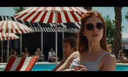 a woman in sun glasses sits in front of a pool