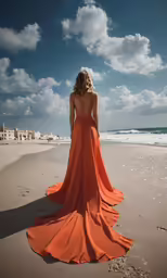 woman in orange dress on sandy beach looking at the ocean