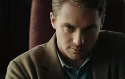 the young man is wearing a sweater and looking away