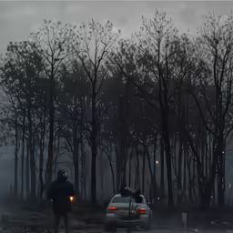 a person holding the door of a car in a forest