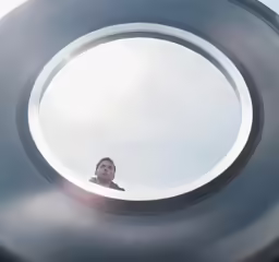 a man is looking out the hole of a tube