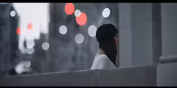 a girl looking out over a wall by some lights