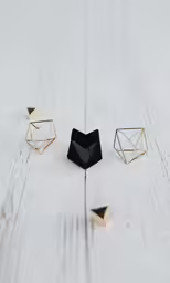 four jewelry pieces on the ground near a wall