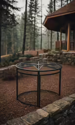 a round firepit in the middle of a wooded area