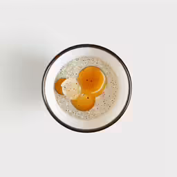 an egg and butter in a bowl on a white table