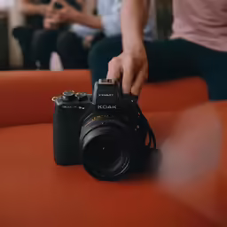 a person holding a camera on an orange couch