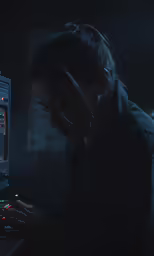 a person sitting with their laptop in a dark place