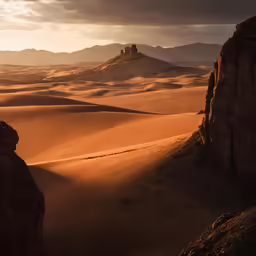 the sun sets over the desert while a couple of rocks sit in the sand