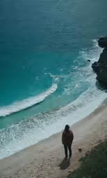 a woman walks along the shore line toward the water
