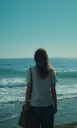 a woman with her hands on her hips is standing at the edge of a beach