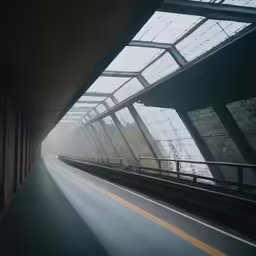 a very long empty road with the sun shining through the windows