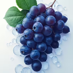purple grapes on white table top next to green leaf