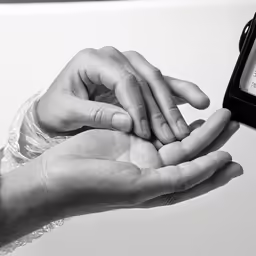 two hands are holding a clock in front of a black and white photograph