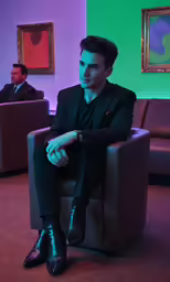 a man in black suit sitting on chair